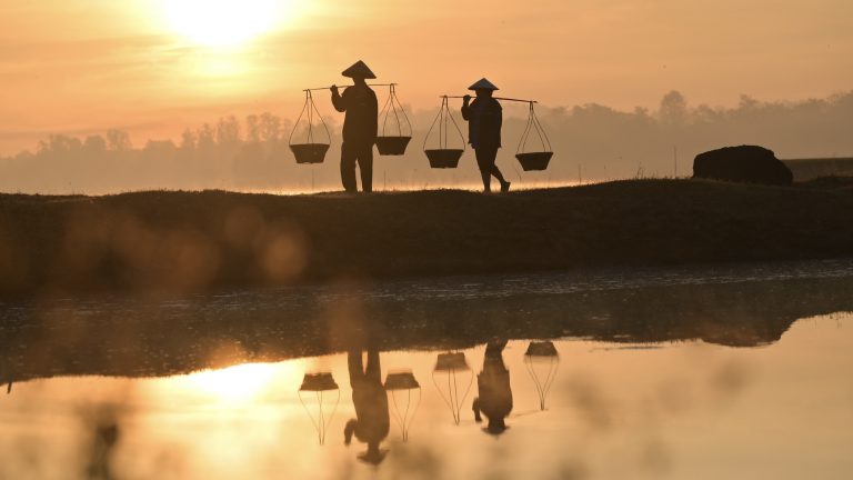 Thai farmers are carrying baskets to prepare to go home before the sun goes down. Silhouette farmer. Silhouette light.